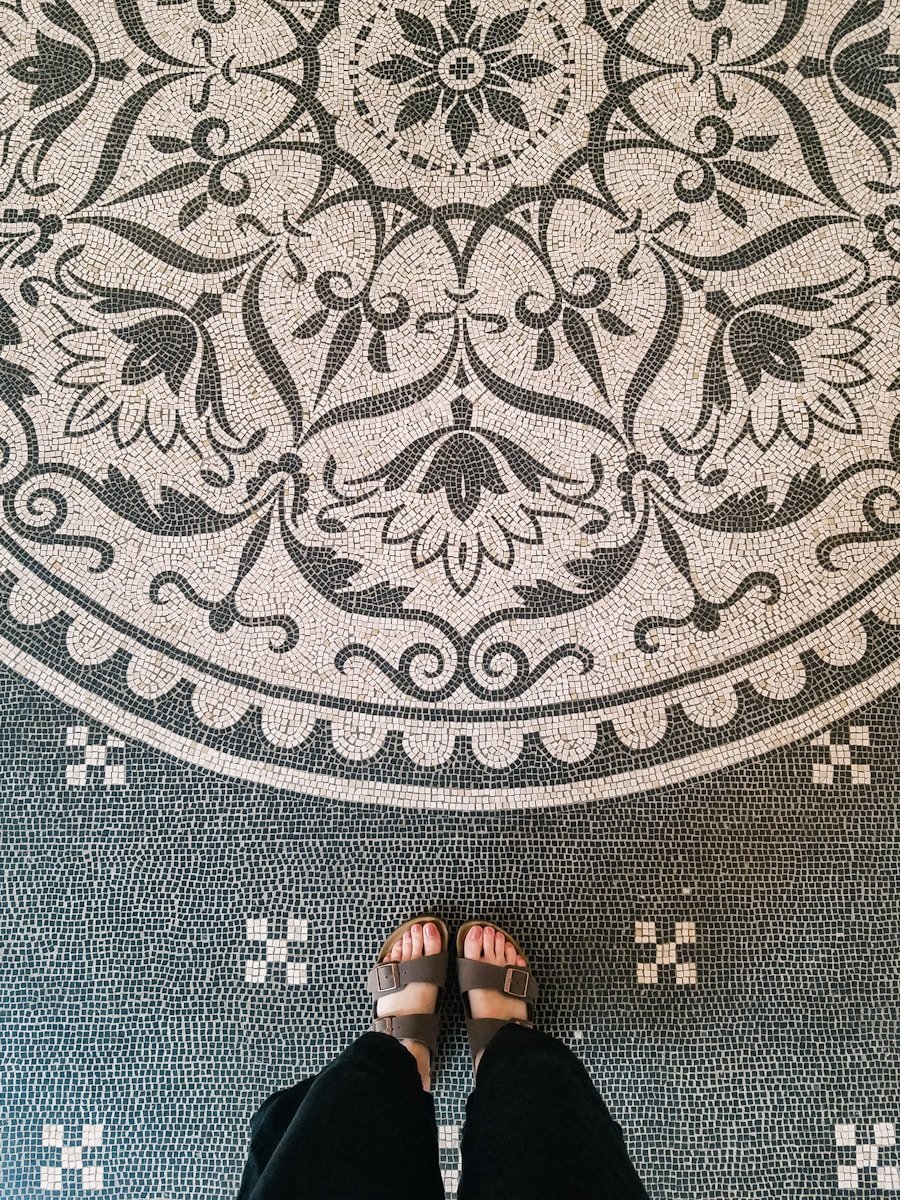 person wearing black flip flops standing on gray and black area rug