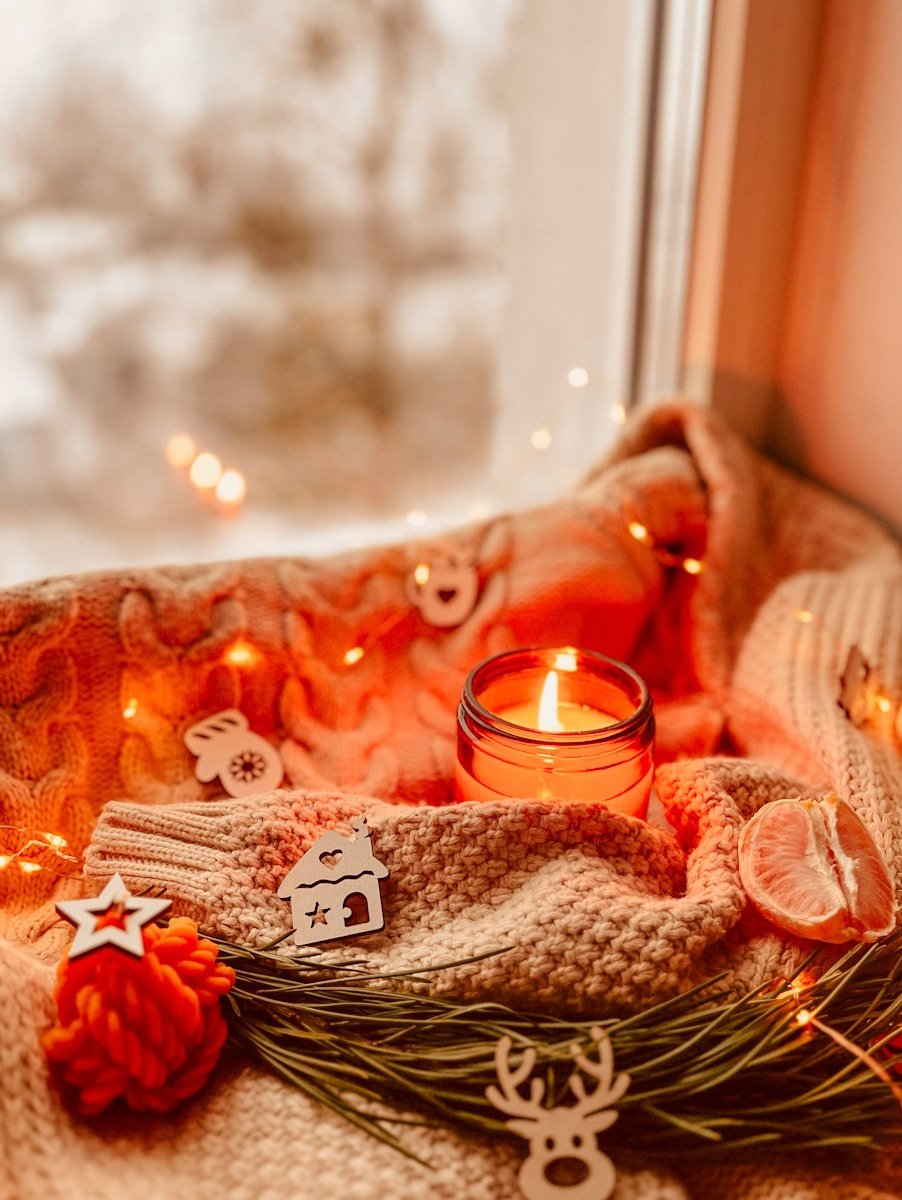 a lit candle sitting on top of a blanket next to a window