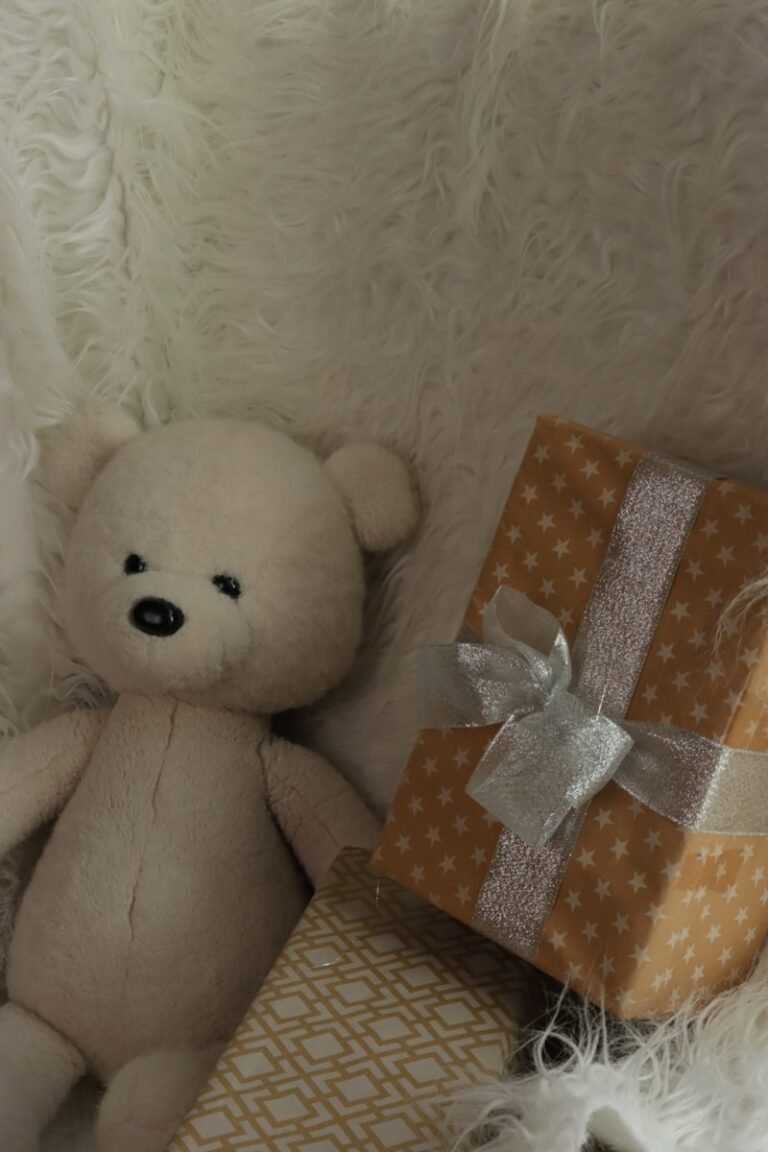 A white teddy bear with two gift boxes