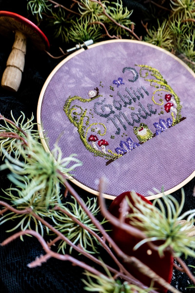 Embroidery hoop with "goblin mode" text and nature elements.