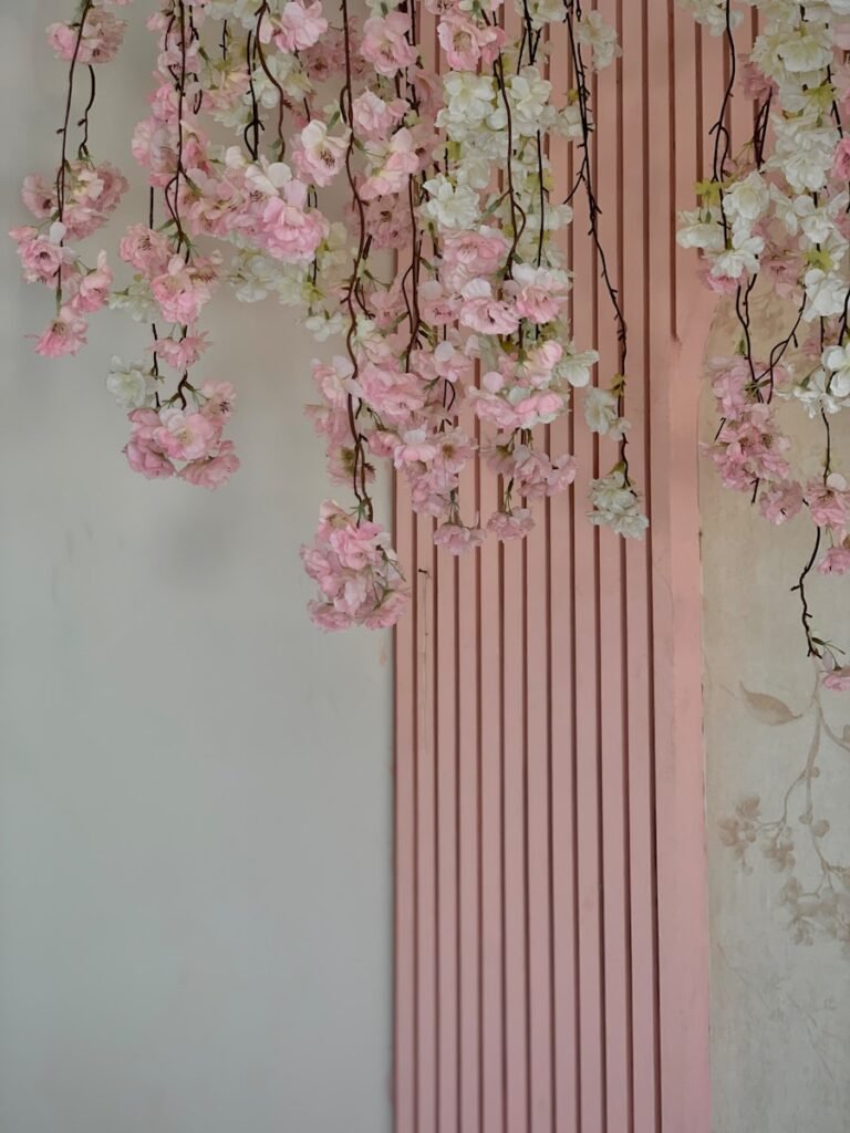 a pink wall with a bunch of flowers hanging from it