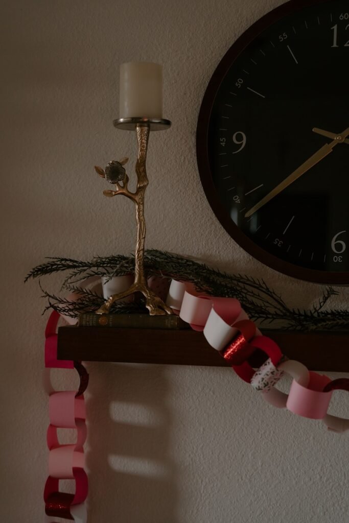 Candlestick and paper chain on shelf near clock.