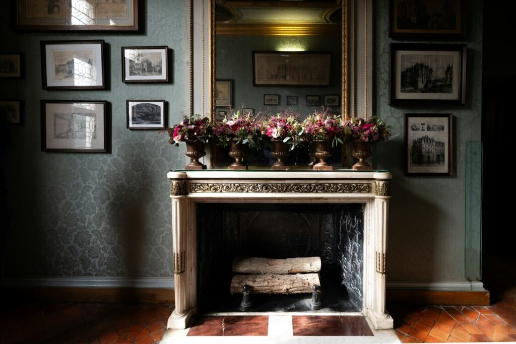 Ornate fireplace with floral arrangements and framed art.