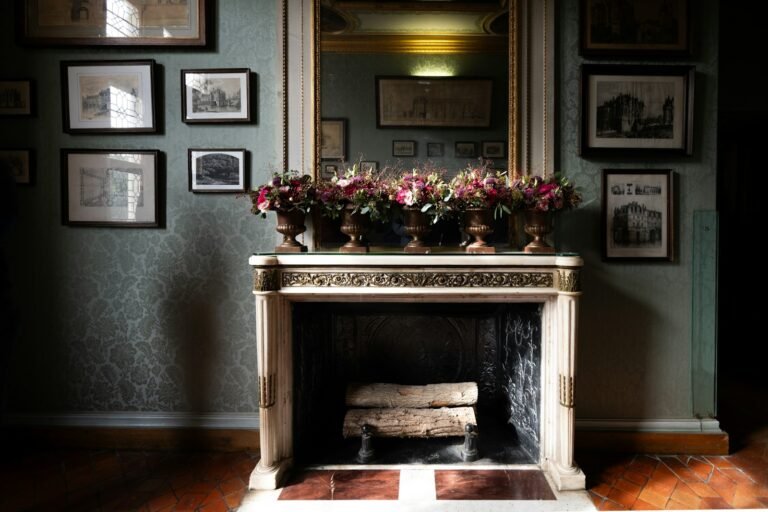 Ornate fireplace with floral arrangements and framed art.