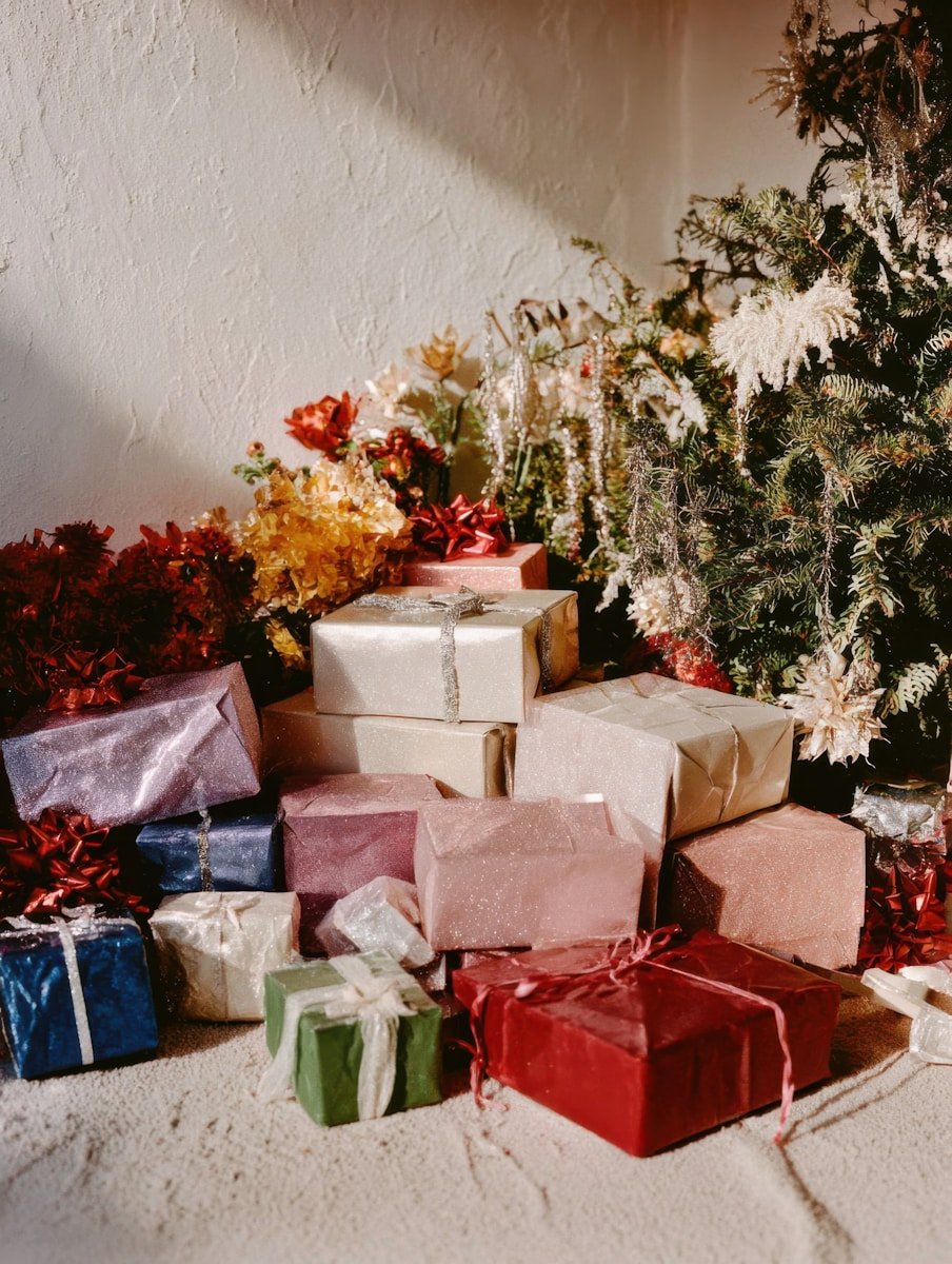 Pile of wrapped gifts near a decorated christmas tree.