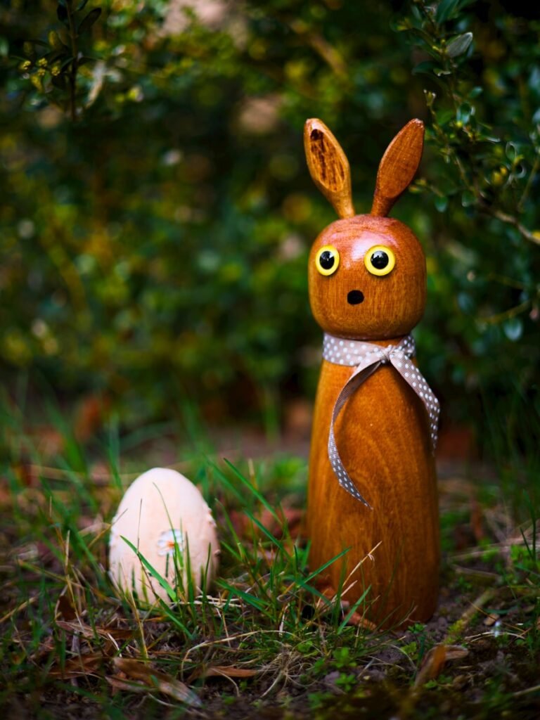 A wooden easter bunny stands next to an egg.