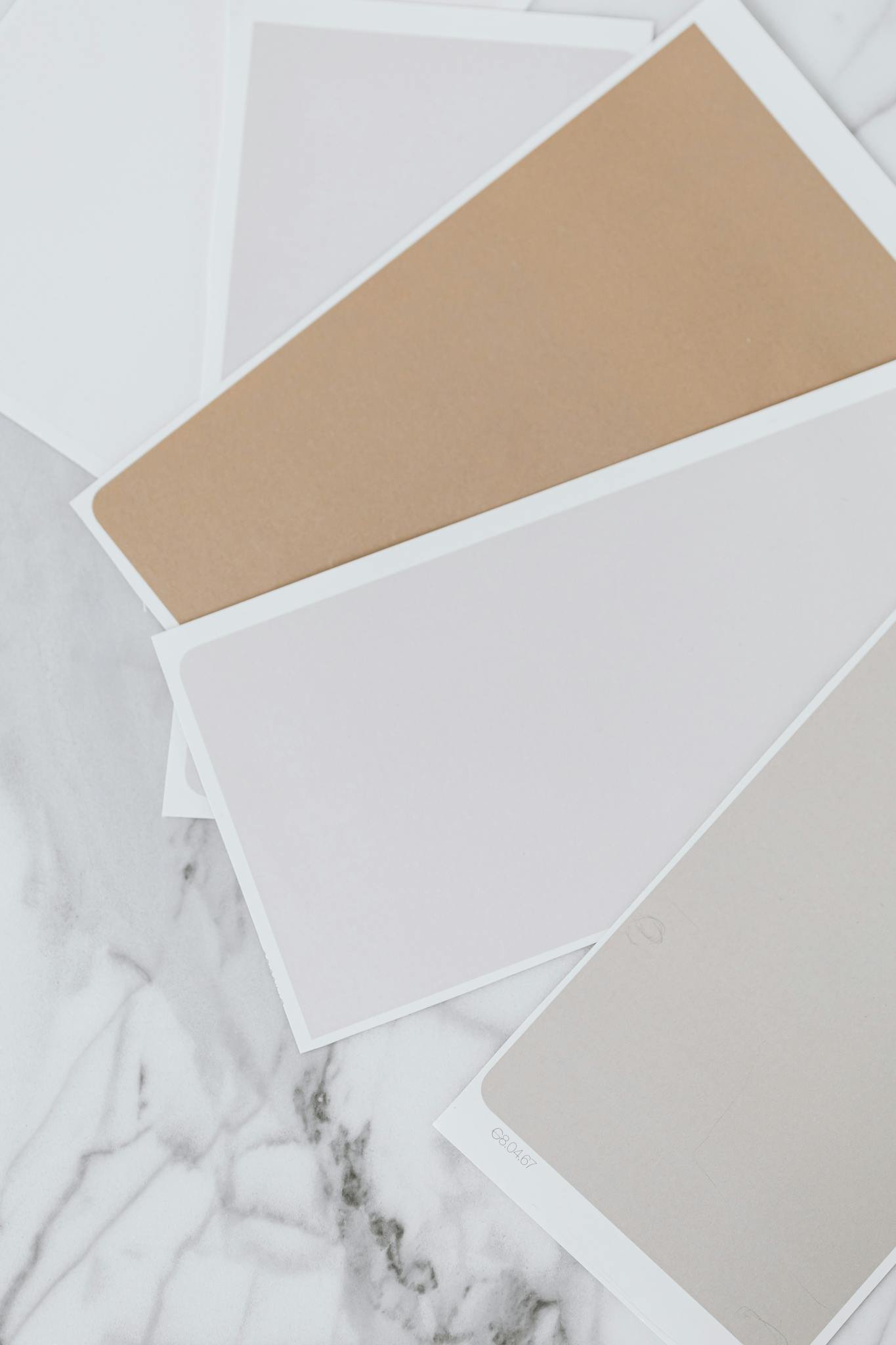 Marble surface with a spread of beige and grey paint swatches, showcasing elegant design options.
