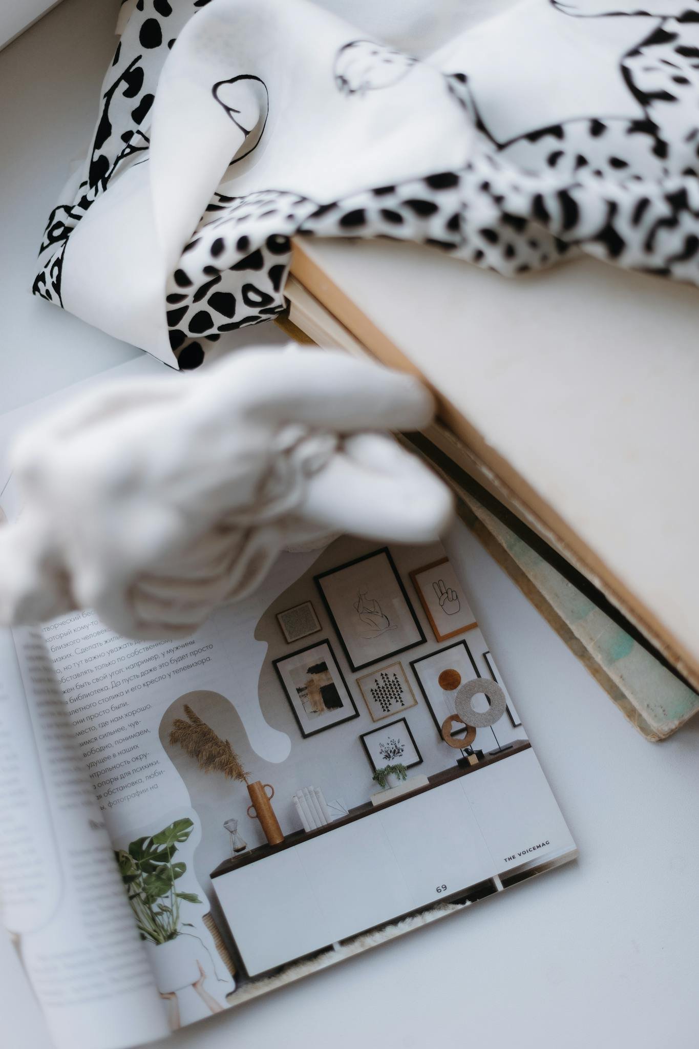 Stylish flat lay of interior design magazine with fabric and sculpture.