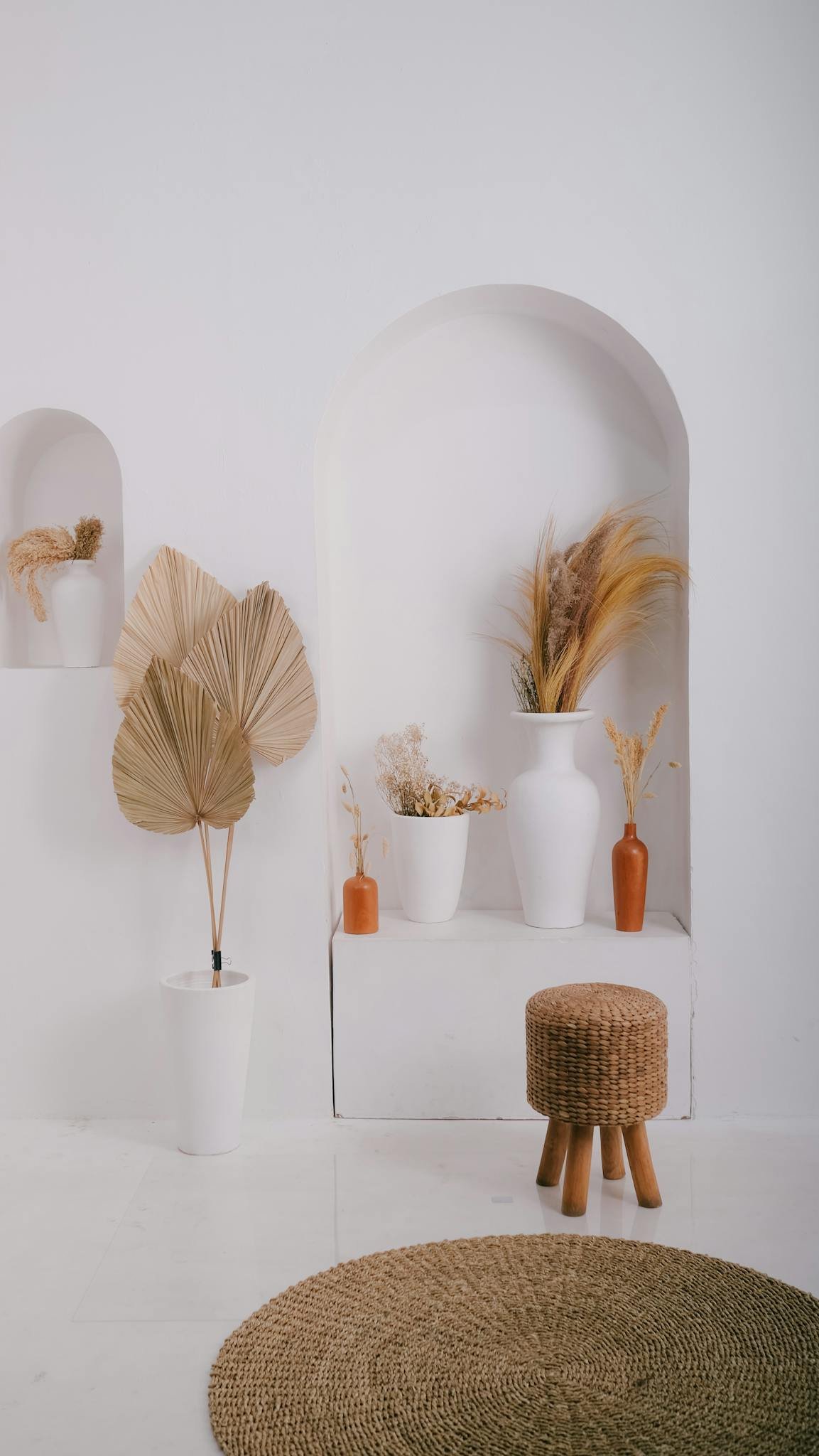 Stylish minimalist interior with neutral tones featuring vases, plants, and a woven stool for a serene ambiance.